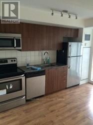 Toronto (South Parkdale) condo for rent - A kitchen with a stove top oven, microwave, refrigerator, and sink.