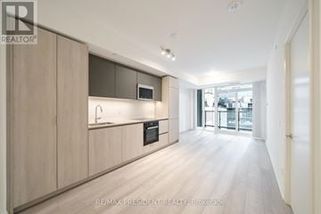 Toronto (Waterfront Communities) condo for rent - A modern kitchen with wooden cabinets and a microwave above the stove.