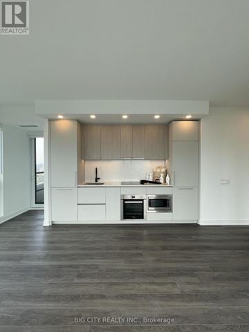 Toronto (North St. James Town) condo for rent - A modern kitchen with white cabinets and a dark floor.