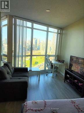 Toronto (Niagara) condo for rent - A living room with a couch, desk, and a view of the city through the windows.