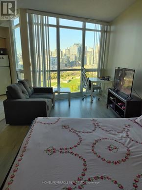 Toronto (Niagara) condo for rent - A living room with a large window overlooking a cityscape.
