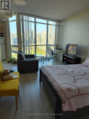 Toronto (Niagara) condo for rent - A bedroom with a bed, desk, and chair with a view of the city.