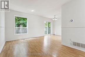 Mississauga (Erin Mills) townhouse for rent - A large, empty room with wooden floors and a window showing greenery outside.