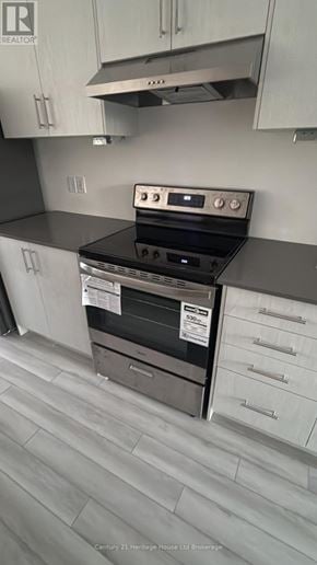 Woodstock (Woodstock - South) townhouse for rent - A kitchen with a stove top oven and a range hood.