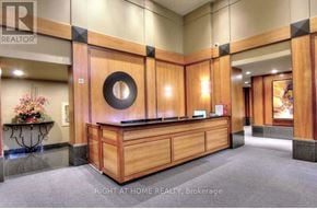 Toronto (Bay Street Corridor) condo for rent - A reception area with a wooden counter and a flower arrangement on a stand.