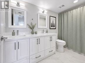 Toronto (Bay Street Corridor) condo for rent - A white bathroom with a toilet, sink, and mirror.