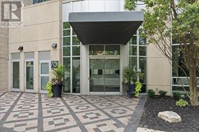 Mississauga (City Centre) condo for rent - The image shows the front of a building with a large glass entrance and a stone walkway leading to it.