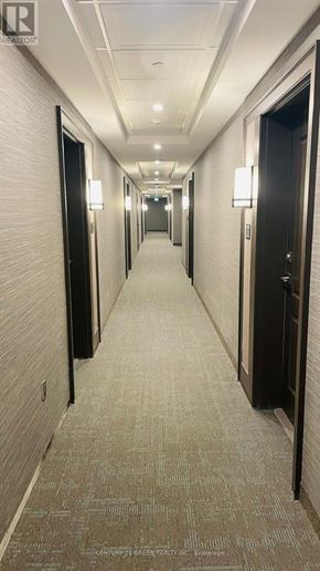 Hamilton (Waterdown) condo for rent - A long hallway with doors on both sides and lights on the ceiling.