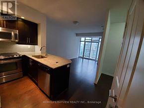 Toronto (Niagara) condo for rent - A kitchen with black cabinets and a wooden floor.