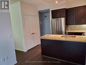 Toronto (Niagara) condo for rent - A kitchen with a white door and a stainless steel refrigerator.