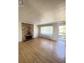 Burnaby apartment for rent - A room with a stone fireplace and wooden flooring.