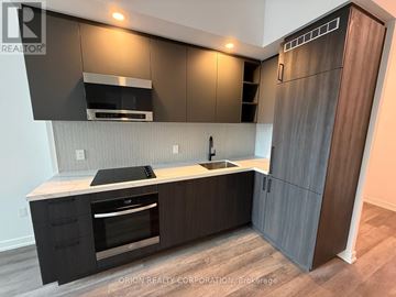 Vaughan (Vaughan Corporate Centre) condo for rent - A modern kitchen with dark brown cabinets and a wooden floor.