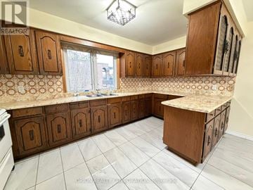 Toronto (Yorkdale-Glen Park) apartment for rent - A kitchen with wooden cabinets and a tiled backsplash.