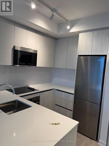 Mississauga (Central Erin Mills) condo for rent - A modern kitchen with white cabinets and stainless steel appliances.