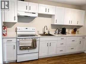 Kitchener apartment for rent - A white kitchen with wooden floors and white cabinets.