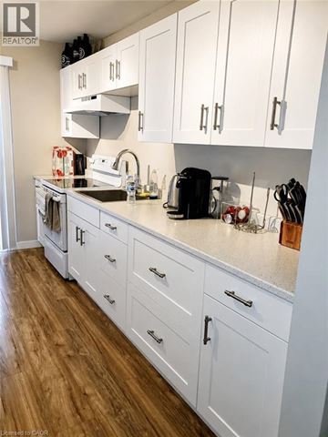 Kitchener apartment for rent - A kitchen with white cabinets and a wooden floor.