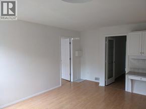 Richmond apartment for rent - A room with a white ceiling and wooden floor with a white cabinet and a black door.