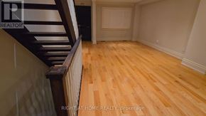 Toronto (Briar Hill-Belgravia) apartment for rent - A room with wooden flooring and a staircase with a wooden railing.