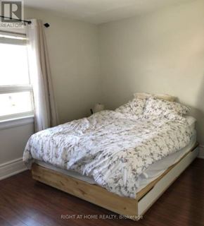 Toronto (Briar Hill-Belgravia) apartment for rent - A bed with a white comforter is in a room with a window.