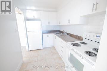 Toronto (Playter Estates-Danforth) condo for rent - A white kitchen with a stove top oven and a refrigerator.