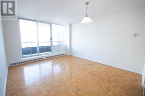 Toronto (Playter Estates-Danforth) condo for rent - A room with a wooden floor and a window overlooking a cityscape.
