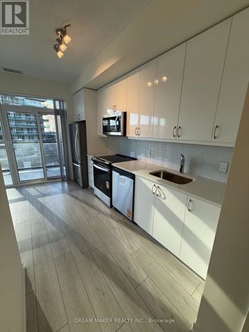 Toronto (Mimico) condo for rent - A modern kitchen with white cabinets and a wooden floor.