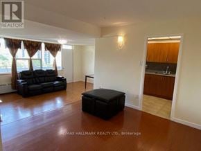 Toronto (Henry Farm) condo for rent - A living room with a black ottoman and a black leather sofa.