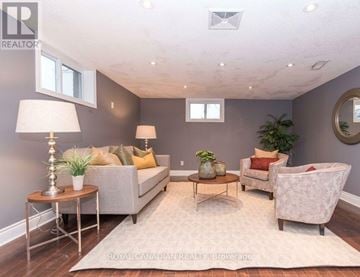 Oshawa (Lakeview) apartment for rent - A well-lit living room with a grey couch, a wooden coffee table, and a white armchair.