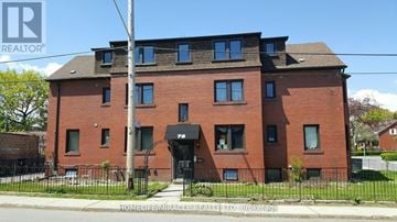 Toronto (New Toronto) multi-family for rent - A red brick building with a black fence in front.