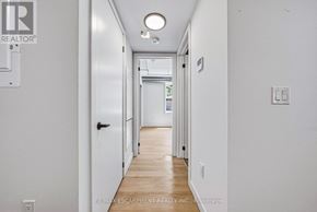 Hamilton (Corktown) multi-family for rent - A long white hallway with a door on the left and a light on the right.