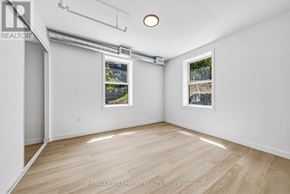 Hamilton (Corktown) multi-family for rent - A room with a white wall and a window with a view of a building.