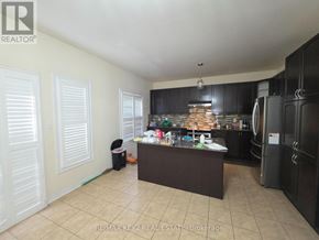 Pickering (Duffin Heights) apartment for rent - A kitchen with black cabinets and a brown island.