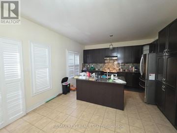 Pickering (Duffin Heights) apartment for rent - A kitchen with black cabinets and a brown island.