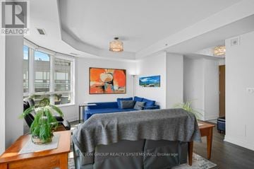 Oakville (Br Bronte) condo for rent - A living room with a grey sofa and a painting on the wall.