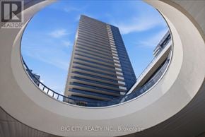 Mississauga (Hurontario) condo for rent - A tall building is seen through a circular frame.