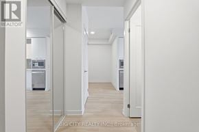 Mississauga (Hurontario) condo for rent - A white hallway with a glass door leading to a kitchen.