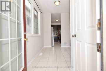 Clarington (Bowmanville) apartment for rent - A hallway with white walls and a tiled floor leading to a kitchen area.