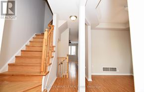 Clarington (Bowmanville) apartment for rent - A wooden staircase with a white wall and a window in the distance.