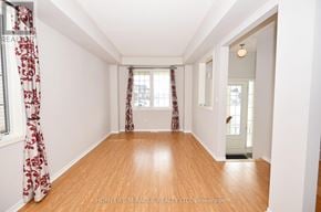 Clarington (Bowmanville) apartment for rent - A room with wooden floors and white walls, with a window covered by red curtains.