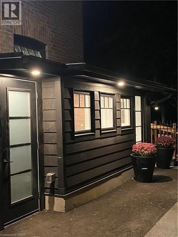 Brantford apartment for rent - A building with a black door and windows with lights on.