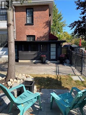 Brantford apartment for rent - A green bench is in front of a brick house.