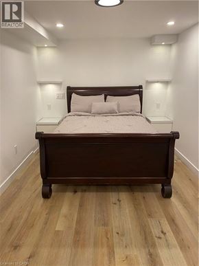 Brantford apartment for rent - A bed with a wooden headboard and footboard sits in a room with wooden flooring.