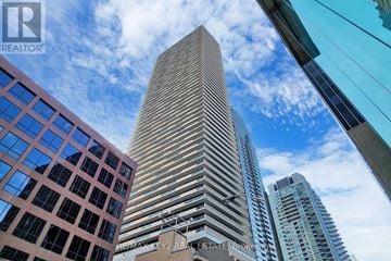 Toronto (Mount Pleasant West) condo for rent - A tall building stands in the middle of a cityscape.