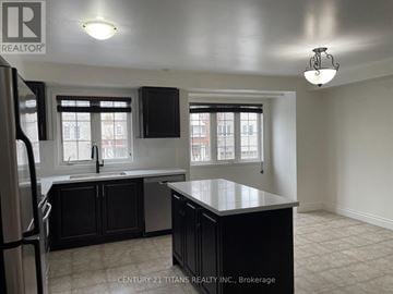 Toronto (Clairlea-Birchmount) townhouse for rent - A kitchen with black cabinets and a refrigerator.