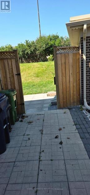 Toronto (Wexford-Maryvale) apartment for rent - A sidewalk with a wooden fence and a green trash can.