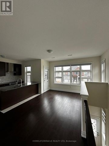 Bradford West Gwillimbury (Bond Head) apartment for rent - A spacious kitchen with dark wood floors and white walls.