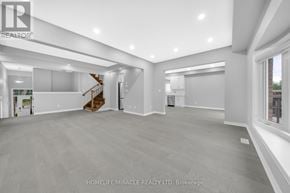 Fort Erie (Ridgeway) apartment for rent - A spacious, empty room with a staircase and a window.