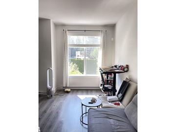 Surrey townhouse for rent - A grey couch sits in a living room with a table and a window.