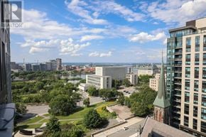 Ottawa house for rent - A view from a high-rise building looking out over a cityscape with a mix of modern and older architecture, a body of water, and a partly cloudy sky.