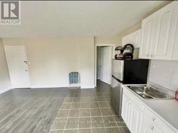Toronto (Clairlea-Birchmount) townhouse for rent - A kitchen with white cabinets and a black fridge.